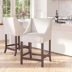 two white bar stools sitting in front of a kitchen counter