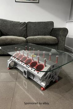 a coffee table made out of an engine is shown in front of a gray couch