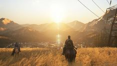 two people riding horses in the middle of a field with mountains and power lines behind them