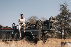 a woman is sitting on the back of a truck with safari gear in it's bed