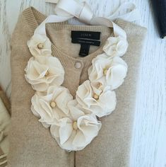 a sweater with flowers on it and a white ribbon