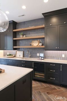 a large kitchen with black cabinets and white counter tops, an island in the middle