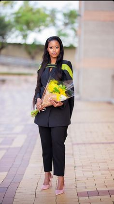 a woman is walking down the street with flowers in her hand