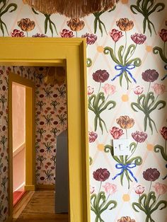 an open door leading into a room with floral wallpaper and yellow trim on the walls