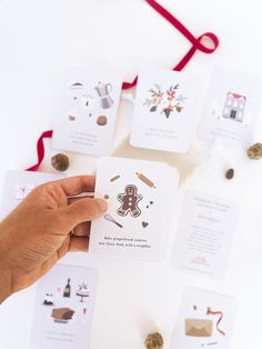 a person holding up some cards on top of a white table with red ribbon around it