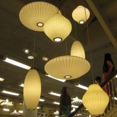 several lamps hanging from the ceiling in a room with people standing on stairs below them