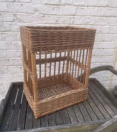 a small wicker birdcage sitting on top of a wooden table next to a brick wall