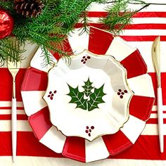 a red and white plate with a green leaf on it next to a christmas tree