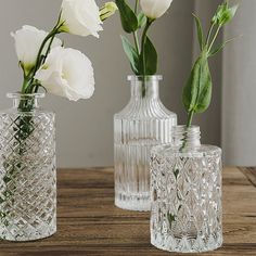 three clear vases with white flowers in them