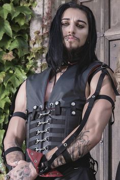 This leather corset, designed with a man's figure in mind, features flat steel boning and reinforced front, back, and modesty panels. The waist cincher is fully lined with black cotton drill fabric, with the outer layer and waistcoat panels made from a soft garment leather. The detachable waistcoat panels and trigger clip fastenings at the front give it an industrial look. The corset has a straight cut and can reduce the waist by up to two inches, making it suitable for any gender. Discover a un Corsets For Men, Fitted Punk Harness For Alternative Fashion, Fitted Black Leather Harness, Gothic Harness For Cosplay, Black Fitted Alternative Corset Belt, Men With Corset, Black Alternative Style Corset Belt, Edgy Fitted Harness For Alternative Fashion, Gothic Black Corset Belt For Larp