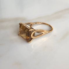 A vintage 9 carat gold ring, displaying a lovely sized citrine. The stone is held by a simple style gold setting that hold the stone up high!  CONDITION: Wear consistent with age and use. Please see photos for more detail. BAND WIDTH: 1mm SETTING HEIGHT: 13mm STONE FACE: 12mm X 14mm RING SIZE: UK: O | US: 7 1/4 WEIGHT: 5.9 grams (UCZ)