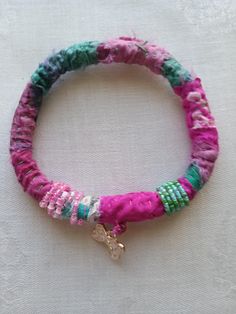 the bracelet is decorated with multicolored beads and a small gold charm on it