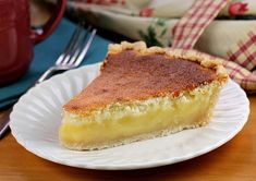 a piece of pie on a paper plate next to a red mug and napkins