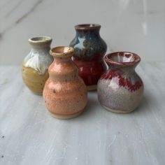 four different colored vases sitting on top of a table