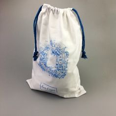 a drawstring bag with a blue design on the front and back side, sitting on a gray surface