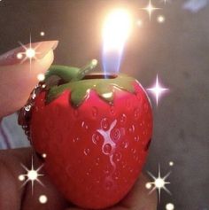 a person holding a strawberry shaped lighter with sparkles on the top and bottom side