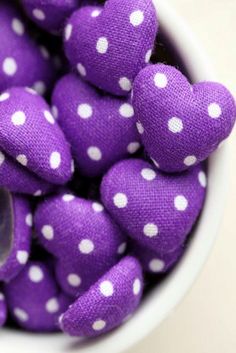 purple and white polka dot fabric hearts in a bowl with a spoon on the side