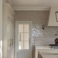 a kitchen with white cabinets and marble counter tops next to an open door that leads to another room