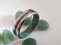 two wedding bands with green jade stones on the ground next to each other and one ring is made out of sterling silver