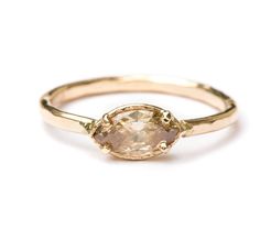 a yellow gold ring with an oval shaped stone in the center and a thin band around it