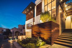 a modern house is lit up at night with lights on the front and stairs leading to it