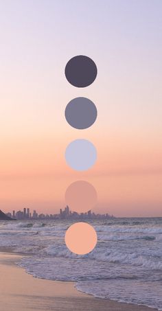 a person standing on top of a beach next to the ocean with circles hanging from them