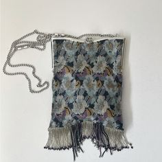 a small purse with tassels hanging from it's side on a white wall