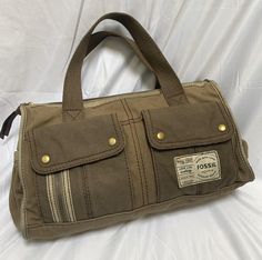 Awesome fun bohoY2K vintage FOSSIL "Long Live Vintage, issue #54" satchel made from army/khaki olive green canvas, with dark gold tone hardware. So many pockets!~ FEATURES: - Double canvas hand straps drop 5" - Two outside back slip pockets - Two outside end slip pockets - Two outside front flap pouch pockets, with mini zip pocket too! - Zippered top closure - Striped cotton lining - Interior zip and two slip pockets Measures 15" x 8" x 5" Condition: Excellent gently used condition. Slight discoloration on interior lining. stock # 6280155 Vintage Satchel, Top Handle Bags, Dark Gold, Zipper Top, Long Live, Y2k Vintage, Pocket Pouch, Army Green, Purses And Handbags