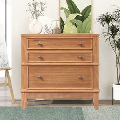 a wooden dresser sitting in a living room next to a plant on top of it