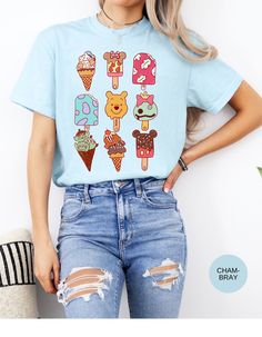 Dive into a world of sweet nostalgia with our "Magical Popsicle Delights Tee"! This charming cotton t-shirt features a delightful lineup of Disney-themed popsicles, each shaped like your favorite characters. Let the magic of these whimsical treats transport you back to your happiest memories. It's a must-have for Disney fans of all ages! Unisex Sizing Terms and Conditions: Returns, Exchanges and Refunds are honored within the first 30 days of purchase. Shipping Times: please expect 4-7 days to r Cute Light Blue T-shirt With Cartoon Print, Casual Crew Neck Tops For Theme Park, Playful Light Blue Cartoon Print T-shirt, Playful Light Blue T-shirt With Cartoon Print, Casual Tops With Character Print For Theme Park, Casual Graphic Print Tops For Theme Park, Whimsical Treats, Happy Memories, Popsicles