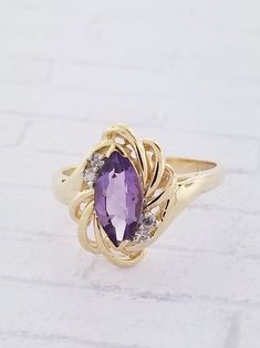 Vintage Amethyst & Diamond ring. This ring features a marquise shaped Amethyst and two diamonds on each side. Details: Size: US 6 1/4 ( Can be sized ) Weight: 3.5 grams Primary stone: Amethyst Stone Shape: Marquise ( Appx. 1.0 tcw. ) Secondary Stone: Diamond Stone Shape: Round ( Appx. 0.06 tcw. ) Metal: 14k Yellow Gold Condition: Brand new Inside of band is stamped and tested for '14k' gold. SIZING: Currently this ring is a size 6 1/4 but could be sized up or down for an additional small fee Formal Marquise Birthstone Ring, Marquise Cut Birthstone Diamond Ring For Formal Occasions, Formal Marquise Diamond Ring With Birthstone, Elegant Amethyst Marquise Ring, Gold Marquise Amethyst Ring, Formal Birthstone Marquise Ring With Diamond Accents, Marquise Birthstone Ring With Diamond Accents For Formal Events, Marquise Birthstone Ring With Diamond Accents For Formal Occasions, Marquise Amethyst Jewelry With Accent Stones