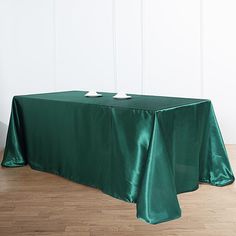 a green table cloth with two white plates on it sitting in front of a wall