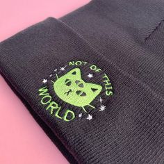 a black hat with a green cat on it's side and the words, not cats world