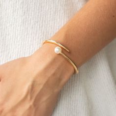 Featuring a solitaire white pearl, two shiny gold bars attach to a spring-like fitting as they curl around the wrist for a modern finish.

Sold as one individual bracelet. Gelang Emas Jewellery, Rings Brand, Pearl Bangle Bracelet, Gold Bracelet Simple, Pearl Bracelet Gold, Pearl Jewelry Design, Gold Bars, Modern Bracelets, Bangles Design