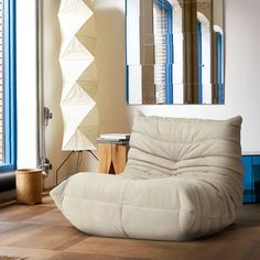 a large white bean bag chair sitting on top of a hard wood floor next to a window