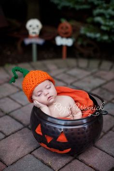 a baby in a pumpkin hat is sleeping inside a caulder with jack - o'- lanterns on it