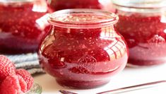 raspberry jam in a glass jar next to fresh raspberries