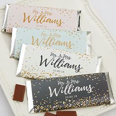 four personalized candy bar wrappers on a white tray with gold and silver confetti