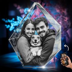 a man and woman holding a dog in front of a crystal photo frame with the image of them on it