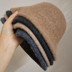 a hand is holding the top of a brown and black hat with stripes on it