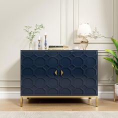 a blue cabinet with gold handles in a white living room next to a potted plant