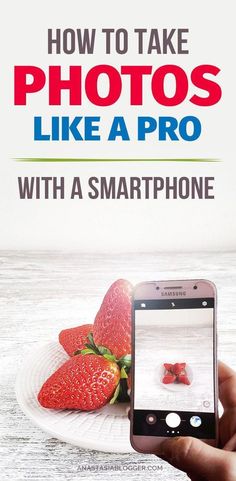 a person holding up a smart phone to take pictures with strawberries on a plate