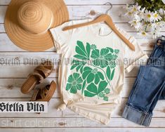 Introducing our Flower Shirt, a must-have for anyone who appreciates minimalist floral designs. Made from high-quality 100% cotton, this Bella and Canvas brand tee is lightweight and comfortable, making it ideal for any occasion. Featuring a large graphic of green flowers, this tee is the epitome of a neutral botanical design. Printed using high-quality ink, this t-shirt avoids the use of itchy vinyl material. The Flower Market top is a versatile choice that can be dressed up or down, while the Floral Tshirt, Neutral T Shirts, Wildflower Shirt, Festival Shirt, Festival Shirts, Botanical Design, Flower Shirt, Flower Market, Green Flowers