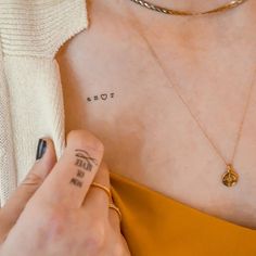 a woman with a tattoo on her left arm holding onto a yellow dress and gold necklace