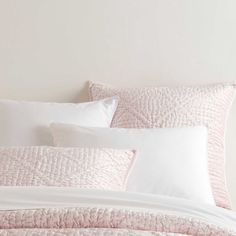 a bed with white and pink sheets and pillows