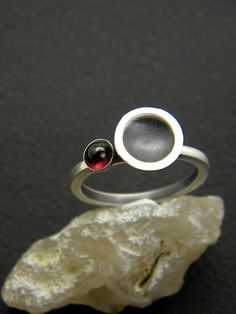 Small garnet ring sterling silver matte finish ring dome disc cup January birthstone, garnet jewelry, gift for her. Contemporary ring in oxidized matte sterling silver Small red garnet gemstone ring in sterling silver.  A reverse domed silver cup blackened with patina and brushed to matte finish and next to it a natural red garnet gemstone The garnet stone is 4 mm cabochon  and the disc is 10 mm in diameter Lovely contemporary ring made in US size 6.5 , UK N , European 54 Here is ring size converter http://www.ringsizes.co/ Garnet stone is January birthstone. If you like have a look at matching earrings. https://www.etsy.com/listing/502966199/silver-garnet-earrings-garnet-sterling?ref=shop_home_active_1 If you need additional information please don't hesitate to contact us. All items arriv Modern Ruby Birthstone Ring, Domed Sterling Silver Jewelry For Gifts, Domed Sterling Silver Jewelry Gift, Sterling Silver Domed Jewelry Gift, Modern Round Ruby Ring, Sterling Silver Dome Ring As A Gift, Sterling Silver Domed Ring Gift, Fork Jewelry, Sterling Silver Garnet Ring