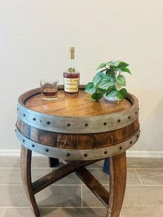 a wooden barrel table with two glasses and a bottle on top that is sitting on the floor