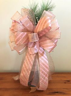 a pink bow on top of a wooden table with a pine tree in the background