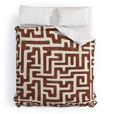 a brown and white comforter set with two pillows on top of the bed, next to an unmade pillowcase