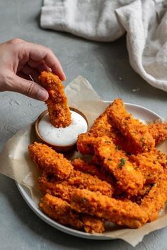 a person dipping sauce on some fried food